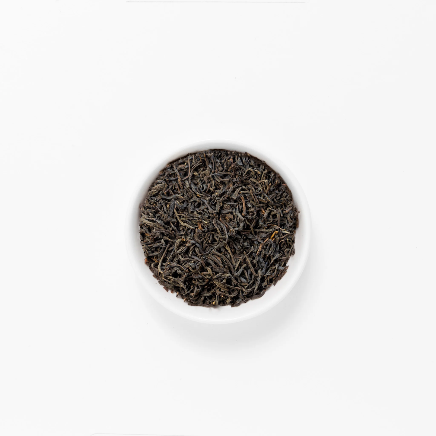 Black tea leaves (Scottish Highlands) in a white bowl on a white background